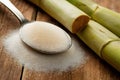 Rustic setup with granulated sugar spoon and sugarcane on wooden surface. Royalty Free Stock Photo
