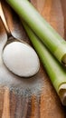 Rustic setup with granulated sugar spoon and sugarcane on wooden surface. Royalty Free Stock Photo