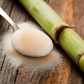 Rustic setup with granulated sugar spoon and sugarcane on wooden surface. Royalty Free Stock Photo