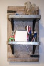 Rustic shelves with barn door backing and metal shelves hanging on wall with tape, note pad, writing instruments and sissors