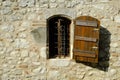 A rustic shuttered window with ornate security bars