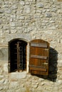 A rustic shuttered window with ornate security bars