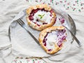 Rustic small galeta pies with fresh berries and vanilla ice-cream on silver dish over a piece of white linen fabric and floral pa Royalty Free Stock Photo