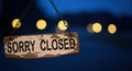 Rustic \'sorry closed\' sign illuminated by warm string lights in evening ambiance Royalty Free Stock Photo