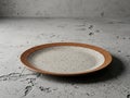 Rustic speckled ceramic plate on a textured grey concrete background Royalty Free Stock Photo
