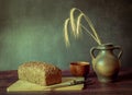 Rustic still life in antique style with bread, ears of wheat . Royalty Free Stock Photo