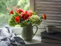 Rustic still life - autumn bouquet of hydrangeas and dahlias in a ceramic jug, books, a cup of green tea on a window with wooden Royalty Free Stock Photo
