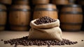 Rustic still life with burlap sack of dark brown coffee beans surrounded by scattered beans and softly blurred barrel background Royalty Free Stock Photo