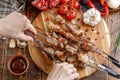 Rustic still life. Juicy pork meat is cut with a knife and fork. Appetizing shish kebabs and fresh vegetables on a wooden backgrou