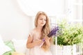 Rustic style bedroom, provence style. Childhood concept. Cute little girl in a dress holds a bouquet of lavender in her hands. A c