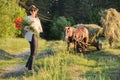 Rustic style, mature happy woman in hat with bouquets of poppies flowers walking along country road Royalty Free Stock Photo