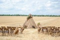 A rustic-style wedding ceremony venue nestled in a rural setting. A triangular wooden arch, adorned with flowers, graces the Royalty Free Stock Photo