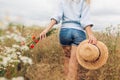 Rustic summer female accessory and clothes. Woman holding straw hat wearing linen shirt and shirts walking in meadow Royalty Free Stock Photo