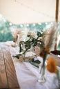 Rustic table decorations outdoors. Flower bouquets, dry wild flowers in glass jars on a wooden tub lying on a festive Royalty Free Stock Photo