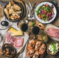 Rustic table set with salad, chicken, brushettas, olives, red wine