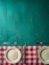 Rustic Table Setting with Empty Plates and Cutlery on Green Wooden Background with Red Checkered Tablecloth