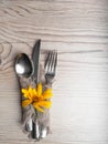 Rustic table setting with linen napkin, cutlery, yellow lower on wooden table. Holiday table decoration. Romantic dinner