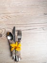Rustic table setting with linen napkin, cutlery, yellow lower on wooden table. Holiday table decoration. Romantic dinner
