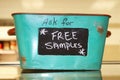 Rustic tin basket sitting on counter that says Ask for free samples