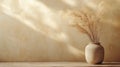 A rustic vase holds delicate dried flowers, casting soft shadows on a warm, minimalistic background Royalty Free Stock Photo