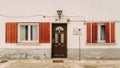 Rustic vintage house featuring red shutters on a white wall in Madrid, Spain.