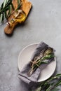 Rustic Vintage Set Of Cutlery. Plate With Grey Linen Napkin, Fork And Spoon, Olive Tree Branch Over Rustic Concrete Gray Old Backg