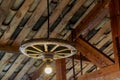Rustic wagon-wheel chandelier hanging from wooden beamed ceiling Royalty Free Stock Photo