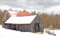 rustic weathered wooden barns with roofs covered in Winter white snow