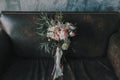 Rustic wedding bouquet with light roses and other flowers on a luxury brown sofa. Close-up. Royalty Free Stock Photo