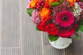 Rustic wedding bouquet with orange, crimson and bordeaux roses, poppy and other flowers and greens on the blurred wooden Royalty Free Stock Photo