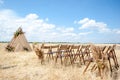 A rustic wedding ceremony setting in a rural locale. A triangular wooden arch, adorned with flowers, stands amidst a golden, mown Royalty Free Stock Photo