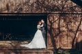 Rustic wedding couple posing and hugging in sunlight at background of wooden wall in country barn. wedding concept, space for text Royalty Free Stock Photo