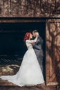 Rustic wedding couple posing and hugging in sunlight at background of wooden wall in country barn. wedding concept, space for text