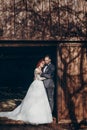 Rustic wedding couple posing and hugging in sunlight at background of wooden wall in country barn. wedding concept, space for text Royalty Free Stock Photo