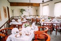 Rustic wedding style. Restaurant interior decorated for wedding dinner, tables with white sheets, fresh flowers and table setting, Royalty Free Stock Photo