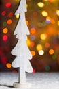 Rustic white wooden tree decoration standing in snow, with christmas tree lights Royalty Free Stock Photo