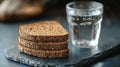 Rustic whole grain bread slices with glass of water on slate board Royalty Free Stock Photo