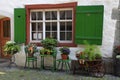 Rustic window with green shutters and flower pots