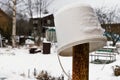 Rustic winter landscape with an old white plastic bucket on an iron rusty pillar.