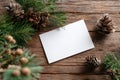 A Rustic Winter Scene Featuring a Blank Card Surrounded by Pine Cones and Evergreen Branches on a Wooden Table Royalty Free Stock Photo