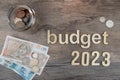 Rustic wood board, bottle of coins, Budget 2023 Royalty Free Stock Photo