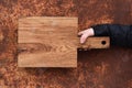 Rustic wood cutting board held in hand on corroded metal texture Royalty Free Stock Photo