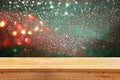 Rustic wood table in front of glitter silver, green, blue and gold bright bokeh lights