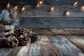 A rustic wooden background with Christmas lights and pine cones in the foreground. Generative AI. Royalty Free Stock Photo