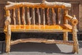 Rustic wooden bench made of rough logs with bark sitting on sidewalk against wooden wall on sidewalk Royalty Free Stock Photo