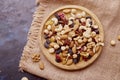 Rustic wooden bowl with assortment nuts, raisins and cranberries on sacking background. Almonds, Hazelnuts , walnuts