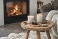 Rustic wooden coffee table close up near cozy fireplace, showcasing weathered texture