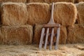 A rustic wooden rake leaning against a stack of fresh hay bales Royalty Free Stock Photo