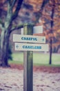 Rustic wooden sign in an autumn park with the words Careful - Ca