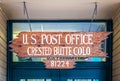 Rustic wooden sign for US Post Office Crested Butte CO handing by chain in front of door - some textured gunge Royalty Free Stock Photo